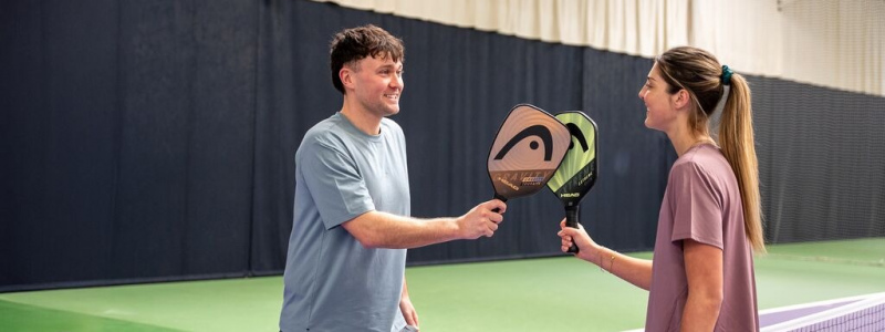 A man and a woman holding pickleball paddles.